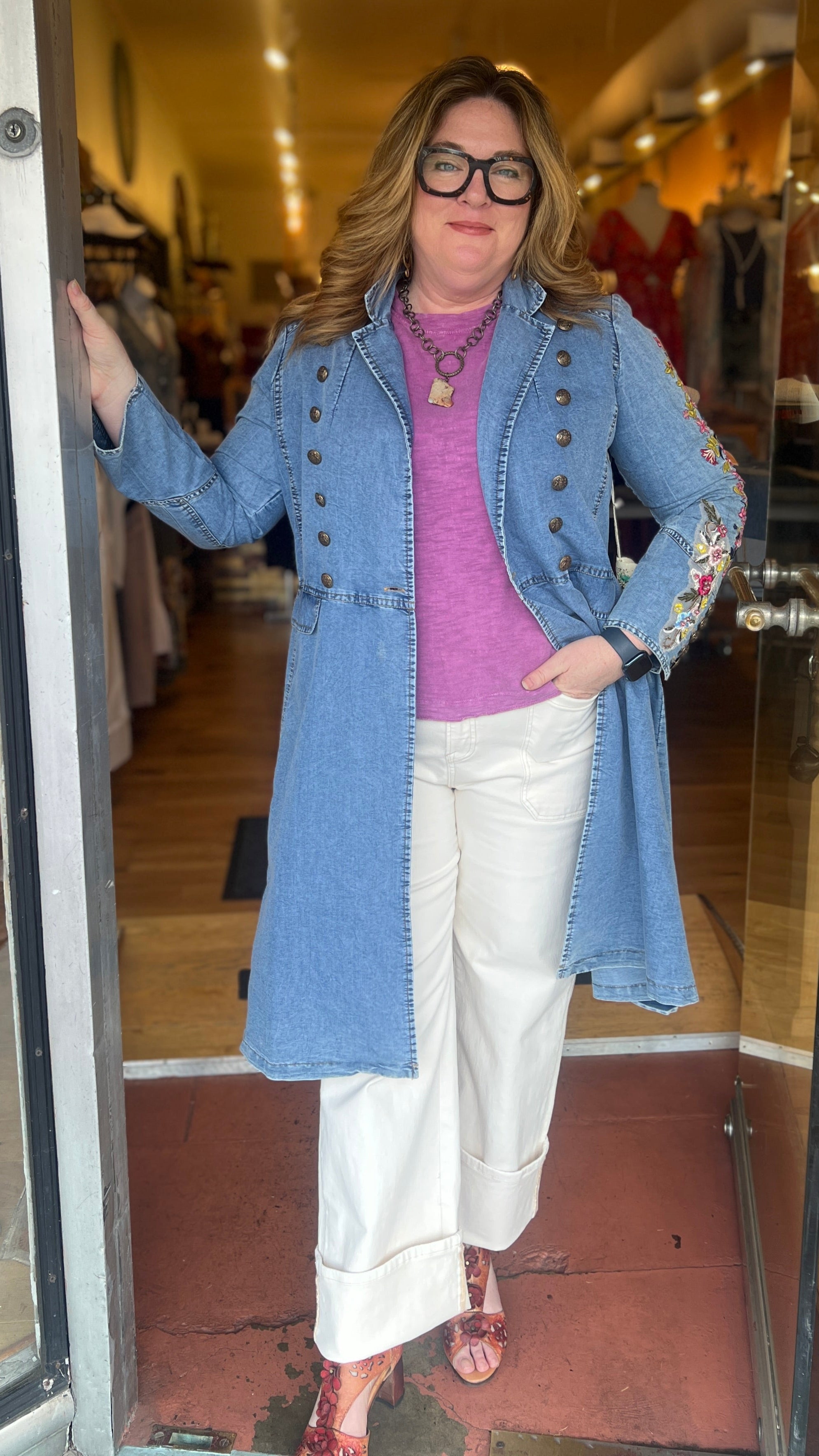 Woman in a blue coat standing in front of a store entrance