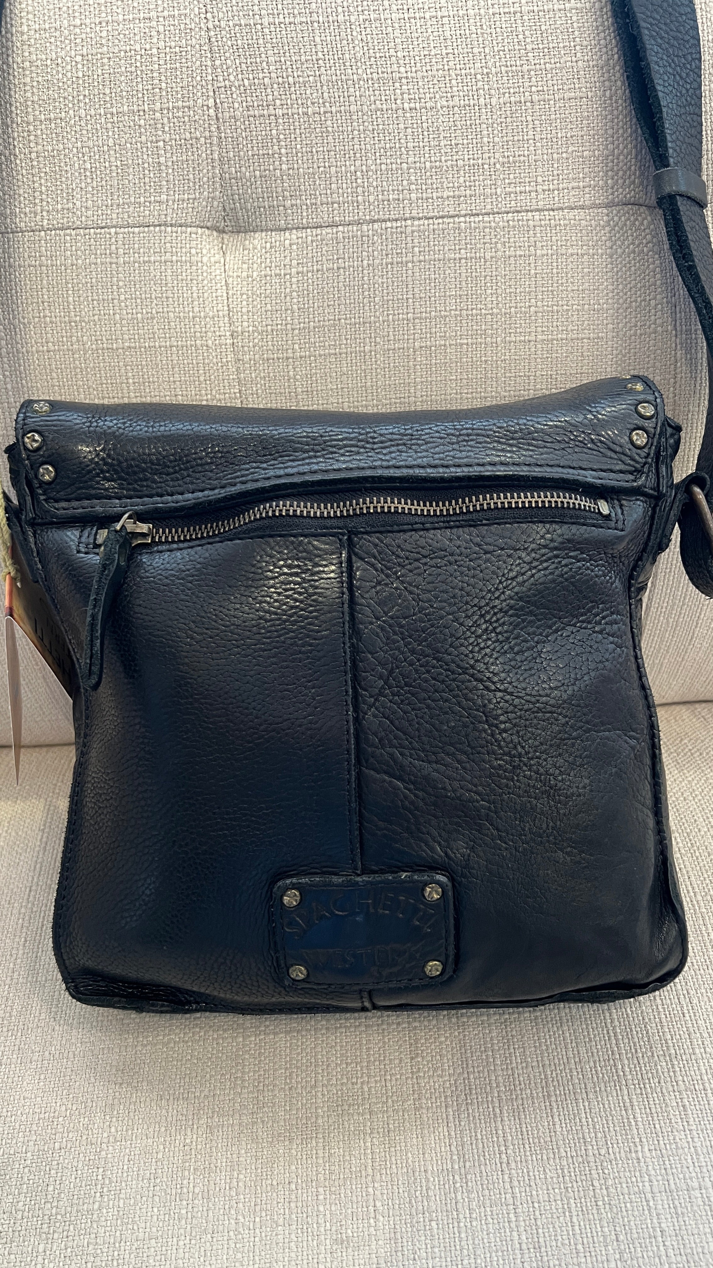 Black leather bag with visible brand logo on a light gray background