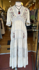 Elegant white dress with embroidery on a mannequin in a store setting.