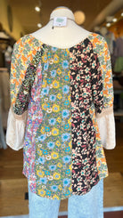 Mannequin wearing a floral patterned top and light blue jeans in a store setting.