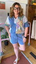 woman standing in a floral short set standin in front of a pink railling
