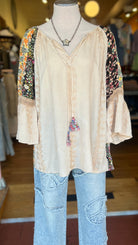 Mannequin wearing a beige blouse with floral sleeves and light blue jeans in a store setting.
