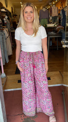 Woman holding a pair of pink floral pants in a store setting