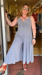 Woman in a gray sleeveless dress standing in a store doorway.