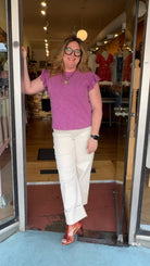 Woman standing in front of a store entrance with mannequins and clothing inside.