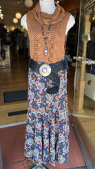 Mannequin wearing a brown sleeveless top and floral dress with a belt in a store setting.